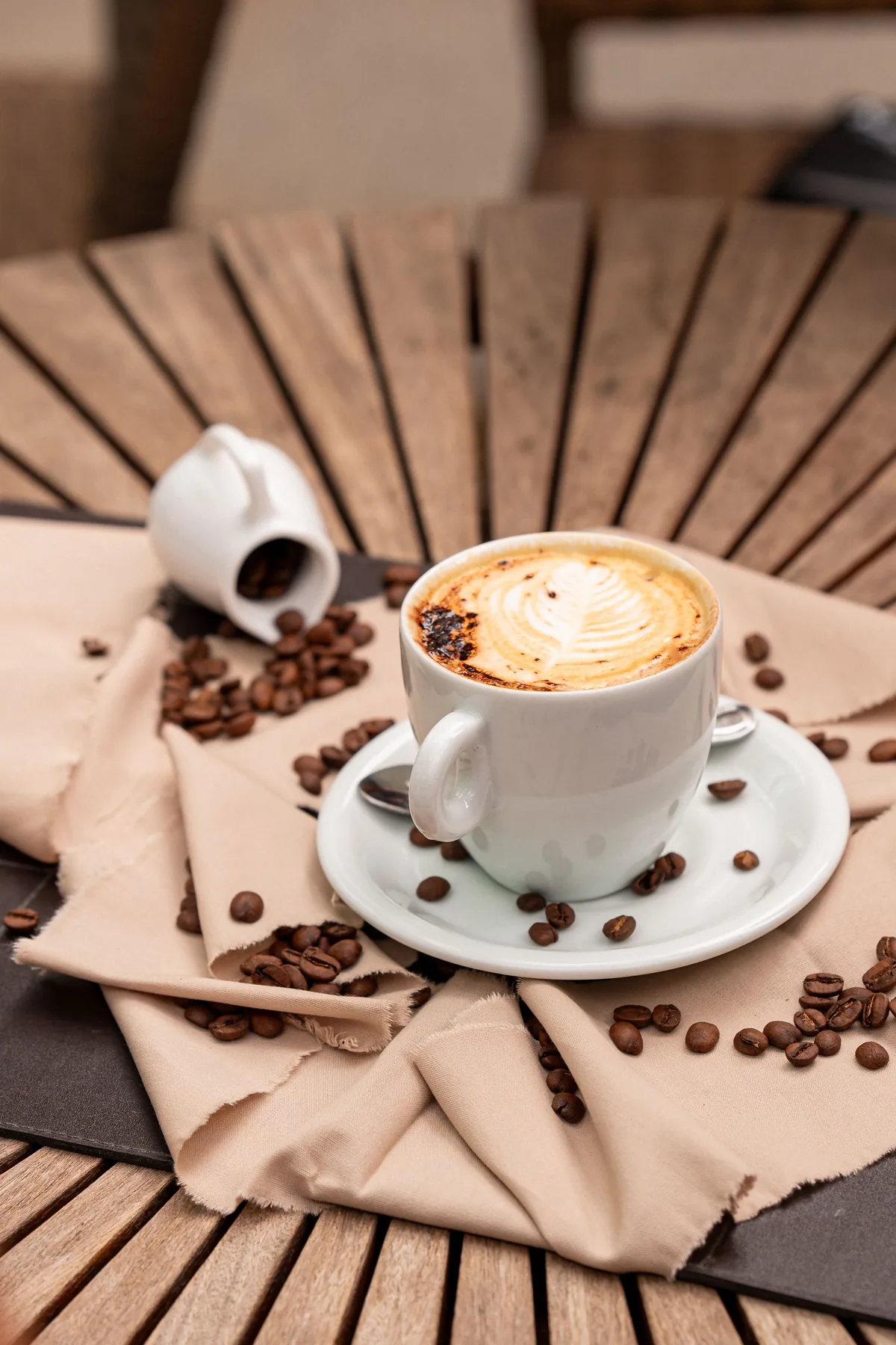 Xícara de café rodeada por grãos sobre uma mesa de madeira